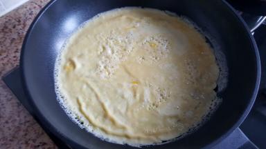 2.不粘锅中放入少量的花生油，将鸡蛋液倒在不粘锅中，摊成鸡蛋饼。