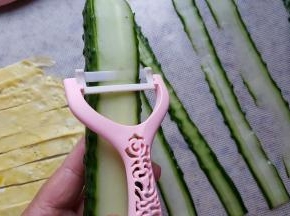 5.把黄瓜洗净，用奈瓷刮刀刮黄瓜片，刮出的黄瓜片薄厚均匀表面光滑且抗氧化能力非常强，黄瓜片放很久也不会有发黄变色的情况，大爱呀，吐槽一下以前的刮刀，刮出的黄瓜片比较厚且不均匀，还会使黄瓜片氧化，编出的菠萝皮颜色也不好看，奈瓷套刀把全部的问题都解决了。