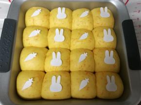 发酵时，剪了胡萝卜和小兔子头像，可爱吗？发酵结束后取出烤盘和水，烤箱预热200度10分钟。把纸模按喜欢的排列放在面团上
