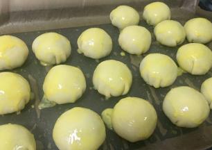 然后用毛刷蘸取蛋黄，依次刷在包好的蛋黄酥表面，可以撒上黑芝麻或杏仁片做装饰。