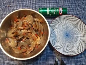 剪掉硬邦邦的虾尾，接着，对准虾头和虾身的交界处，将这个地方剪断三分之二，留着三分之一连接头身，从剪开的缺口处，沿着虾背的背脊线剪开（不但要剪开虾壳，还要剪开三分之二厚度的虾肉，留下三分之一来连接保持虾肉不会散开），接着，将剪开的虾身部分左右分开、摊开。