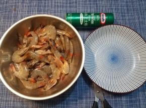 剪掉硬邦邦的虾尾，接着，对准虾头和虾身的交界处，将这个地方剪断三分之二，留着三分之一连接头身，从剪开的缺口处，沿着虾背的背脊线剪开（不但要剪开虾壳，还要剪开三分之二厚度的虾肉，留下三分之一来连接保持虾肉不会散开），接着，将剪开的虾身部分左右分开、摊开。
