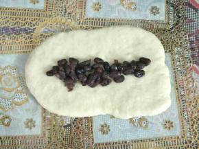 铺上适量蜜红豆横着卷起，捏紧收口