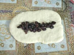 铺上适量蜜红豆横着卷起，捏紧收口
