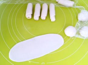 松弛好的面团用擀面杖擀成长条，长度比手掌长一点即可，之后卷起来，盖保鲜膜松弛15分钟