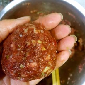 5. 电饭煲中放入500克高汤，再加入适量的水，烧至沸腾，取一点肉馅，两手倒换轻摔，直至滚圆，放入锅中，先将按键调至保温