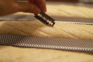 将发酵好的面包胚取出，用刀片割好三或五条斜切口