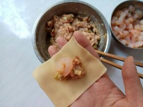 取一个馄饨皮，包入肉馅，再加一个虾仁。
