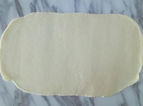 静置好的白糖水面团，用擀面杖擀成面皮