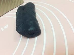黑色面团也是擀成长方形 撒少量小颗的提子干 自下而上卷起 但不要卷到头 留1公分左右
