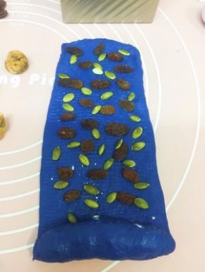 在剩下面片上撒提子干和南瓜子 卷起捏紧收口