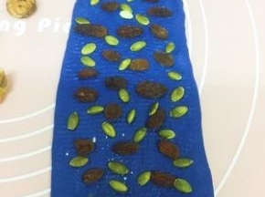 在剩下面片上撒提子干和南瓜子 卷起捏紧收口