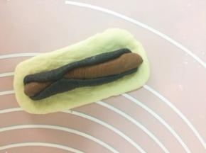 取一块可可面团 擀长卷起 黑色面团也擀长 将可可面团包入 收口无需捏紧 随意一些 白色面团同样擀长 包入黑色可可面团 收口捏紧