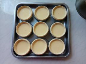 将挞水糊用小勺逐个盛到蛋挞皮里，保持9分满状态。每个蛋挞皮盛30ml左右蛋挞水，按这个配料，全部用完，完美。