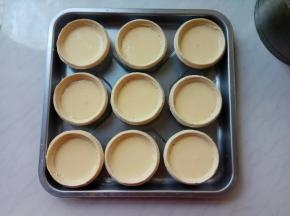 将挞水糊用小勺逐个盛到蛋挞皮里，保持9分满状态。每个蛋挞皮盛30ml左右蛋挞水，按这个配料，全部用完，完美。