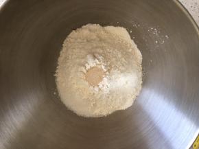 盆内倒入高筋面粉，盐和糖对角线放置，中间挖一小孔倒入活性干酵母