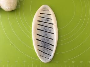 用擀面杖擀成椭圆，用刀片斜着割10多刀，从长边开始卷起