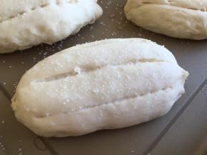 进行第二次发酵，二次发酵因为室温不够我利用了烤箱，发酵档（37度），烤箱内放一杯清水，发酵40分钟，面团到原来的1.5倍大小，用羊毛刷轻轻刷一层牛奶，刀片竖着割3刀，撒上粗粒砂糖