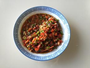 把青椒、红椒、小米辣丁和翻炒好的佐料拌匀，可尝一下味道，咸味要比平时炒菜咸一点儿，因为要用来烤茄子