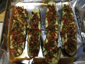 蒸好的茄子放在铺了锡箔纸的烤盘上，把准备好的佐料均匀铺在茄子上，往茄子的网格缝里塞一些佐料，把剩余料汁浇在茄子上