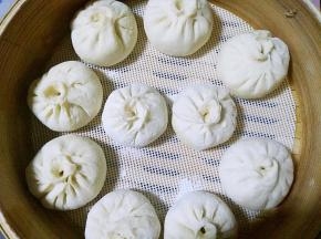 在每一张面皮上放入适量的馅料包成包子均匀的摆放在陶煲王蒸锅的笼屉上面。盖上盖子进行二次发酵。