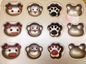 将红曲面糊挤入猪的耳朵、鼻子和猴子的鼻子。三个脚印部分分别挤入抹茶面糊、可可面糊、红曲面糊。眼睛挤入可可面糊。送入烤箱180度烤2分钟。
