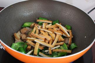 把肉片、香干倒入锅中翻炒；