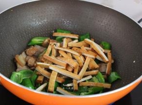 把肉片、香干倒入锅中翻炒；