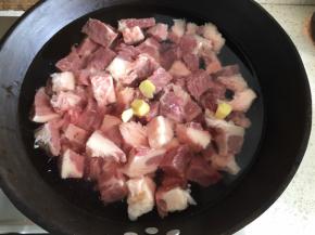 解冻的肉逆着牛肉的纹路切成3cm的方块，冷水下锅，倒入适量料酒，加入姜片，开火，煮开后2分钟，关火
