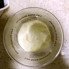 6.沿杯壁挤入一层淡奶油，左手拿杯子，右手拿裱花袋，左手缓慢旋转