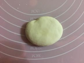 揉出气体后，取出1/5的面团，平均分成两份，揉成椭圆形，按扁。