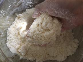 把低筋面粉过筛加入容器内，加入软化的黄油丁，用手搓成粗玉米面状态