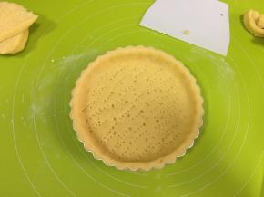 把面皮放在6寸派盘上，按压与派盘粘合，擀去多余的面皮，与小面团混合，用叉子在派皮底部插上小孔，防止派皮烤的时候凸起