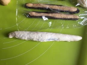 牛奶面团搓成比可可面团长的长条，擀扁，全部包裹住两种有颜色的面团