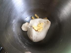 启动厨师机3档，搅拌到面图案呈扩战阶段，倒入软化的黄油，继续和面