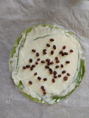 把淡奶油抹平，边缘尽量不要抹到，上面在撒入适量的蜜红豆。