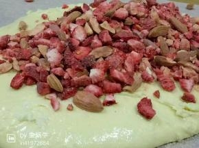 小火将黄油软化倒入棉花糖，黄油和棉花糖混合化成糖料糊后分三次加入奶粉，快速拌匀倒在提前铺好的吸油纸上加入敲过的草莓冻干和杏仁碎，再次拌匀在12寸金色牛轧糖烤盘里整成长方形糖块；