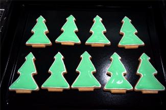 将绿色的稀糖霜装入裱花袋，然后给圣诞树填上主体色，然后放置一旁晾干。