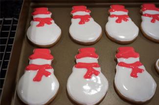 在等待手套饼干晾干的过程，用白色稀糖霜给雪人填上主题色，然后用红色稀糖霜画上帽子和围巾，画好后放置一旁晾干。