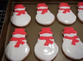 在等待手套饼干晾干的过程，用白色稀糖霜给雪人填上主题色，然后用红色稀糖霜画上帽子和围巾，画好后放置一旁晾干。