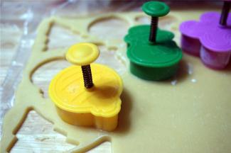 在面片上印出饼干坯：先按压模身，后按压中间的弹簧印出花纹。