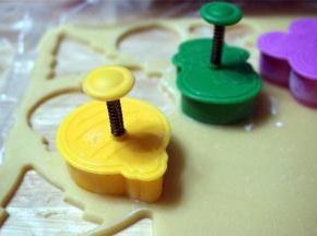 在面片上印出饼干坯：先按压模身，后按压中间的弹簧印出花纹。