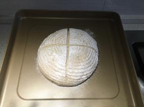 把面团倒扣在烤盘上，筛上高粉，用刀片割两刀