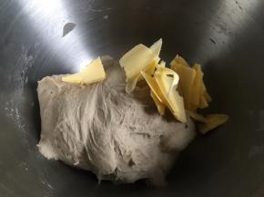 倒入清水开启厨师机和面，面团揉到起筋，加入黄油，继续揉面