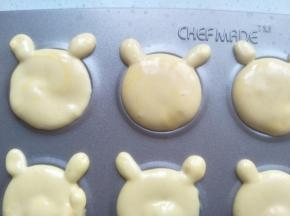 再拿一个裱花袋，剪小一点的口，挤上两个小圆形做耳朵。余留的面糊同样操作