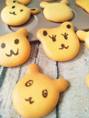 待饼干凉后，用黑色色素笔画上小熊的眼睛、鼻子五官等