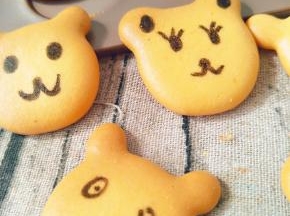 待饼干凉后，用黑色色素笔画上小熊的眼睛、鼻子五官等