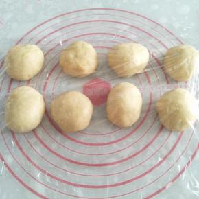 取出面团进行排气，均匀分成8个小面团。将面团放在案板上，用手将面团滚成圆球形。盖上保鲜膜松弛15分钟