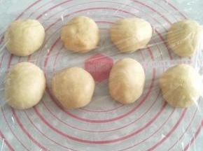 取出面团进行排气，均匀分成8个小面团。将面团放在案板上，用手将面团滚成圆球形。盖上保鲜膜松弛15分钟