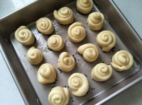 将面卷整齐的排放在烤盘中。盖上保鲜膜，放温暖处进行第二次发酵